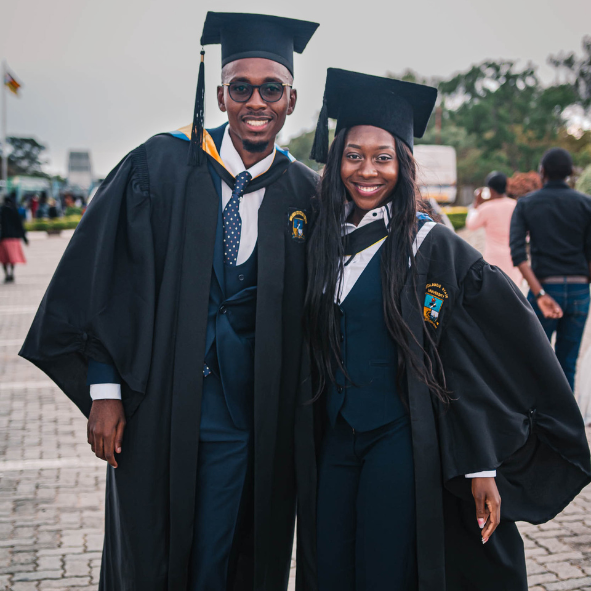 A Black man and woman in a graduation cap and gown. 